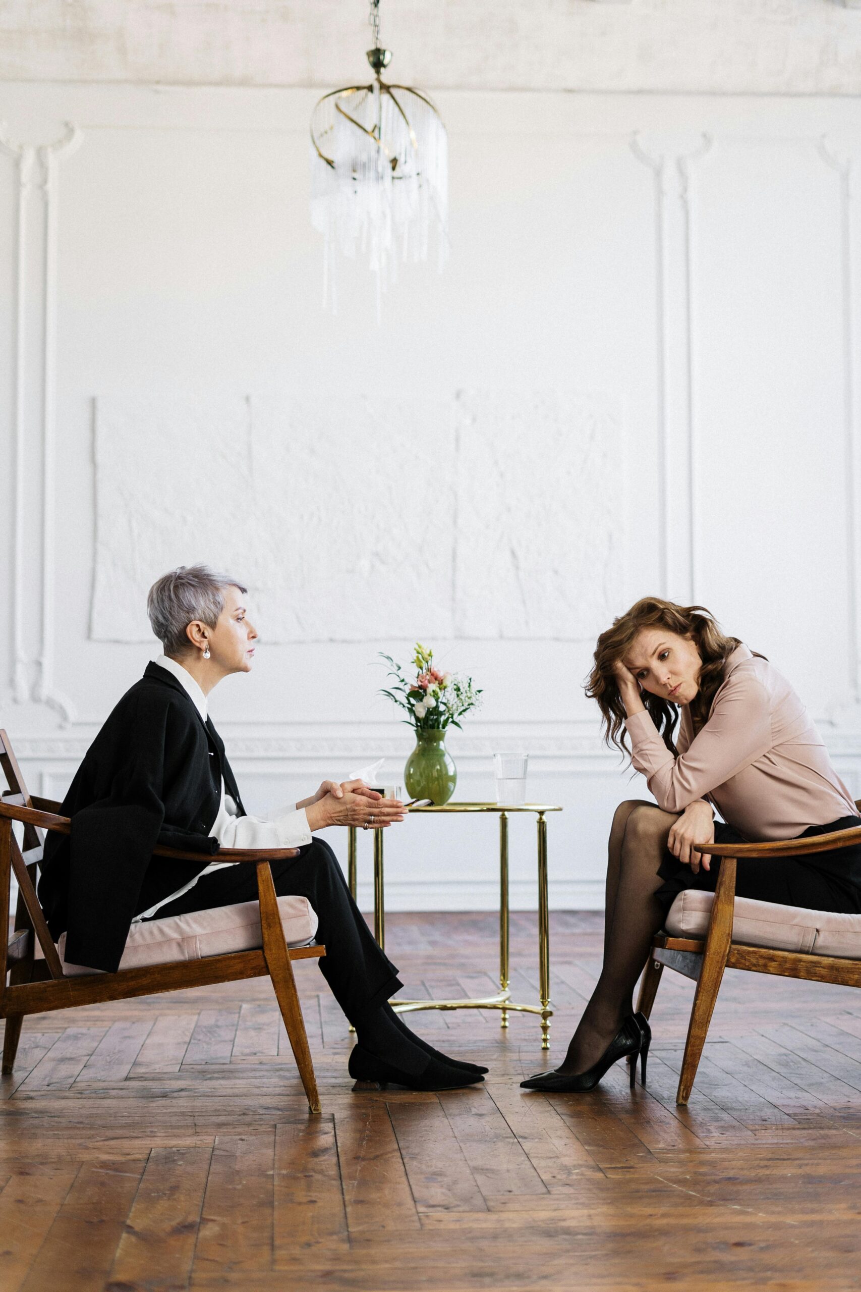 Two women engaged in a counseling session, discussing mental health indoors.